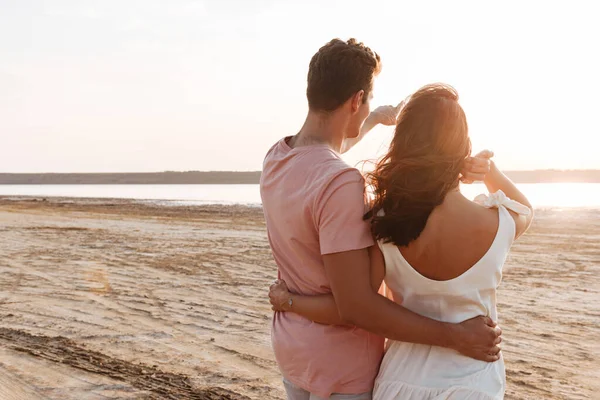 Όμορφο νεαρό ζευγάρι που φοράει καλοκαιρινά ρούχα στέκεται στην παραλία — Φωτογραφία Αρχείου