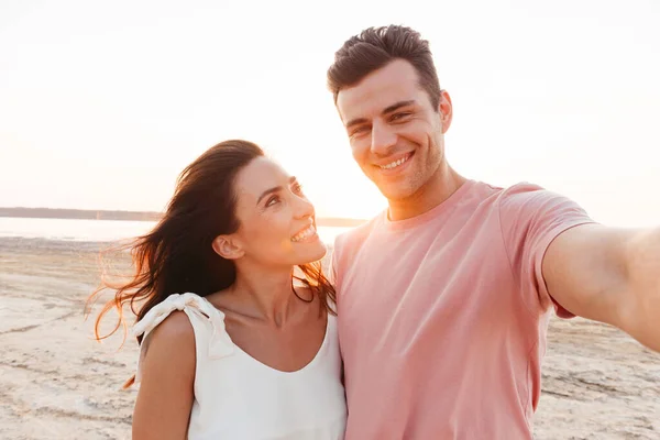 Schönes junges Paar in Sommerkleidung steht am Strand — Stockfoto