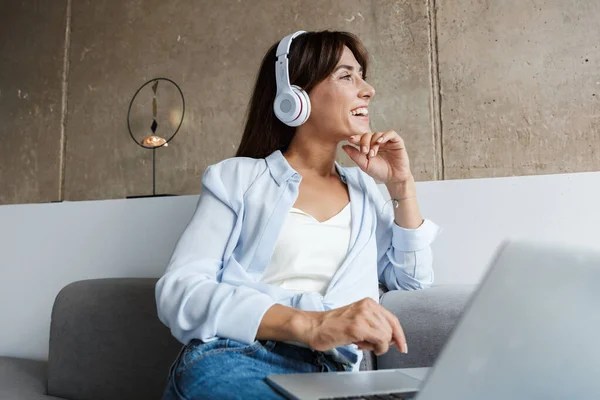 Frau zu Hause hört Musik mit Kopfhörern — Stockfoto