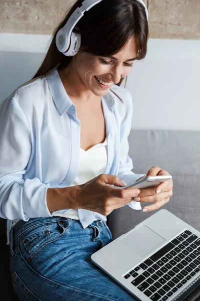 Woman indoors at home chatting by mobile phone. — Stock Photo, Image