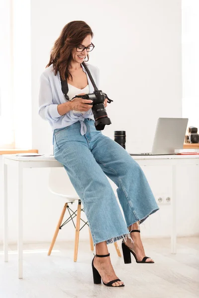 笑顔楽観的な若い写真家女性でオフィスでカメラ. — ストック写真
