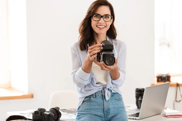 陽気幸せな笑顔若いです可愛いですカメラマン女性でオフィス開催レトロ古いカメラ. — ストック写真