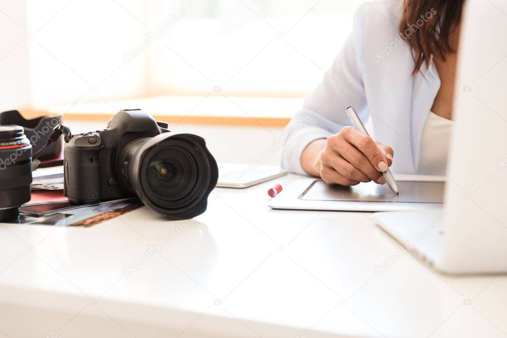 Photographer woman in office sit at the table with camera working by graphic tablet retouching photos.