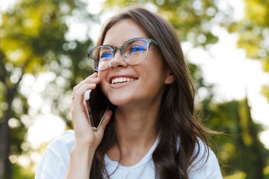 Doğal yeşil parktaki bayan cep telefonuyla konuşuyor..