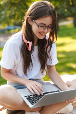 Otoparkta dizüstü bilgisayar kullanan bir kadın.