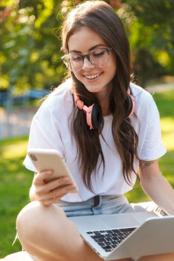 Bayan dışarıda dizüstü bilgisayar ve cep telefonu kullanıyor..