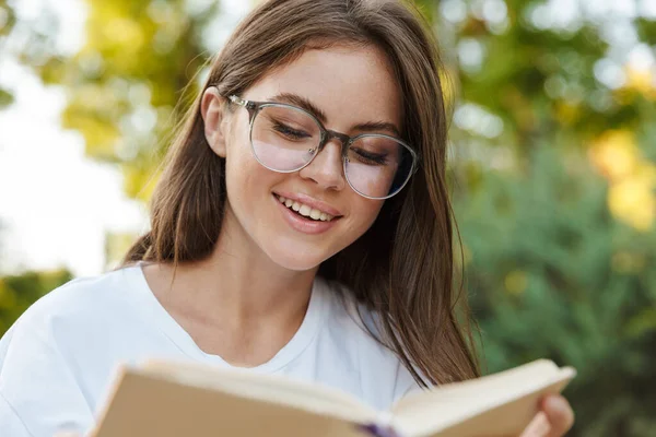 Χαμογελώντας νεαρό κορίτσι ανάγνωση ένα βιβλίο — Φωτογραφία Αρχείου