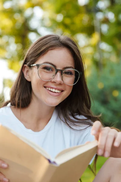 Χαμογελώντας νεαρό κορίτσι ανάγνωση ένα βιβλίο — Φωτογραφία Αρχείου