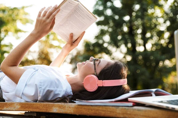 Lady luisteren muziek met koptelefoon op copybooks lezen boek. — Stockfoto