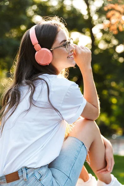 Dışarıdaki kadın yeşil parkta kulaklıkla müzik dinliyor.. — Stok fotoğraf