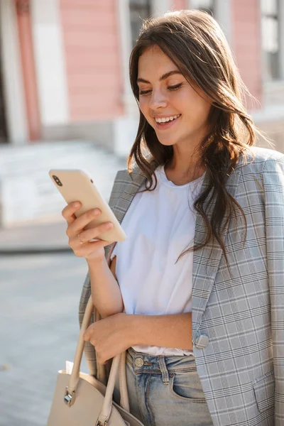 Stijlvolle vrolijke zakenvrouw op straat met behulp van mobiele telefoon. — Stockfoto