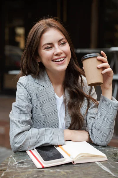 Gyönyörű fiatal nő ül a kávézóasztalnál a szabadban — Stock Fotó