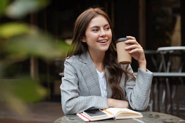 Beautiful young woman sitting at the cafe table outdoors — Stock Photo, Image