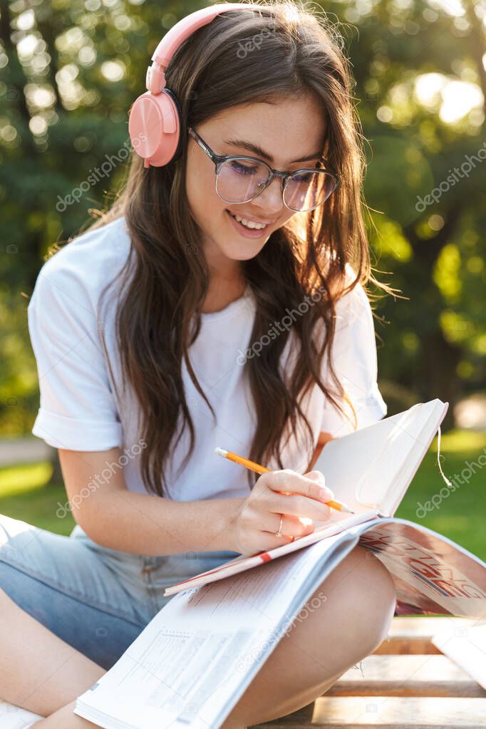 Lady outdoors in nature green park writing notes in notebook.