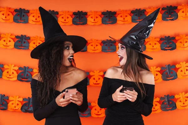 Imagen de mujeres brujas en traje de halloween negro sosteniendo el celular —  Fotos de Stock