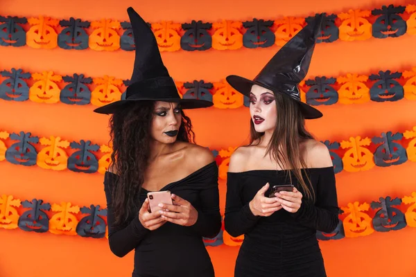 Bild av häxkvinnor i svart halloween kostym kika på cellp — Stockfoto