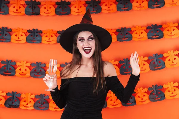 Obraz czarownicy dziewczyna w czarny halloween kostium gospodarstwa szampan — Zdjęcie stockowe