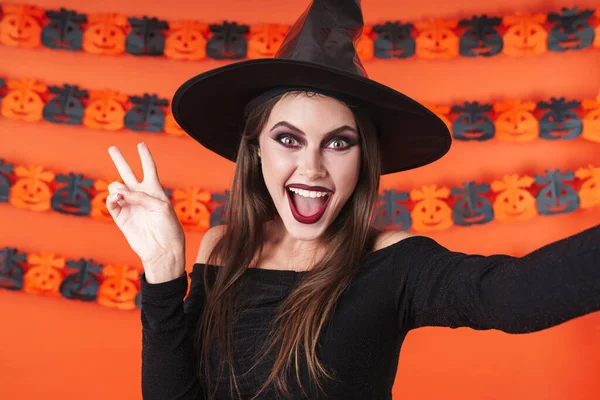 Imagen de chica bruja mística en traje de halloween negro mostrando pe —  Fotos de Stock