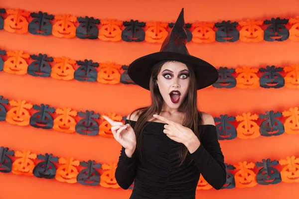 Imagem da bruxa chocada em traje preto halloween apontando — Fotografia de Stock