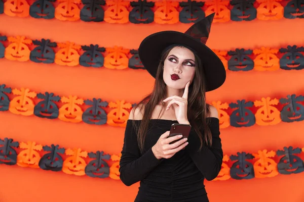 Imagem da bruxa menina em traje preto halloween segurando smartphon — Fotografia de Stock
