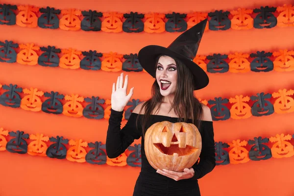 Imagen de chica bruja excitada en traje de halloween negro sosteniendo c —  Fotos de Stock