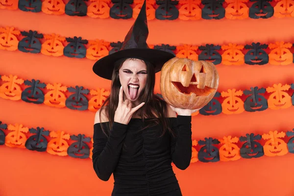 Imagem da bruxa menina em traje preto halloween segurando esculpida pu — Fotografia de Stock