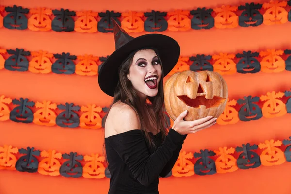 Imagem da bruxa menina em traje preto halloween segurando esculpida pu — Fotografia de Stock