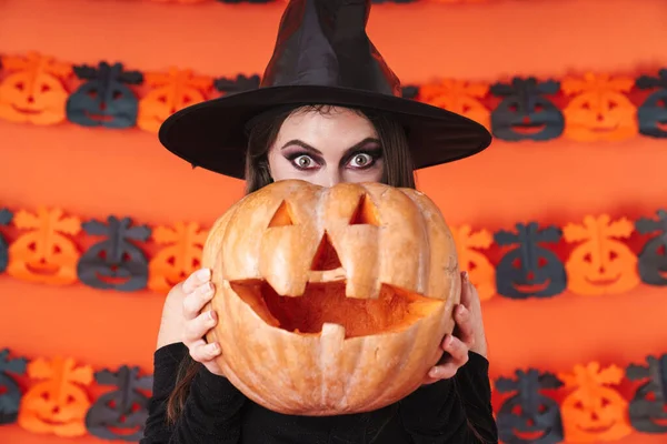 Imagem da bruxa menina em traje preto halloween segurando esculpida pu — Fotografia de Stock