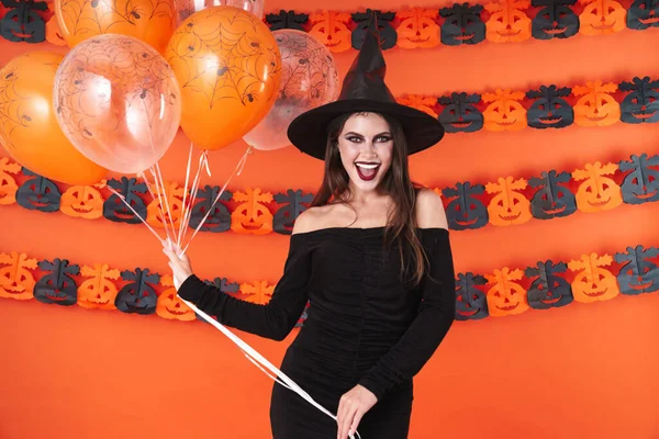 Imagen de chica bruja en traje de halloween negro sosteniendo globos —  Fotos de Stock