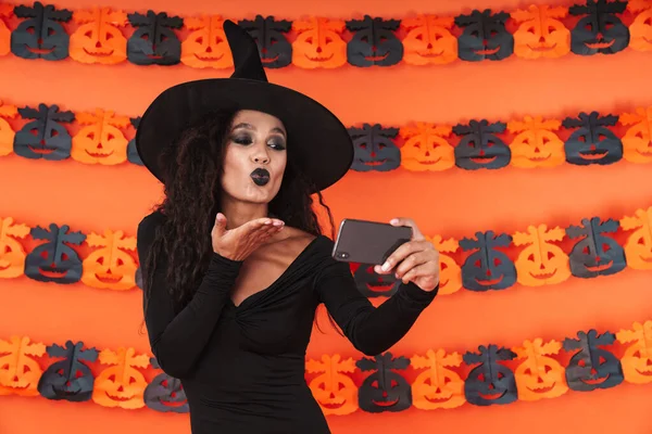 Imagen de glamour chica bruja en traje de halloween negro tomando se —  Fotos de Stock