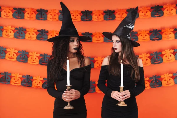 Imagen de mujeres brujas asustadizas en traje de halloween negro sosteniendo ca —  Fotos de Stock