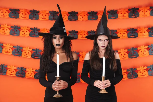 Imagen de mujeres brujas enojadas en traje de halloween negro sosteniendo ca — Foto de Stock