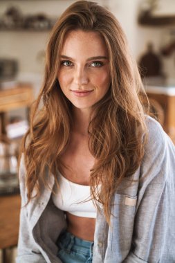 İyimser, mutlu, mutlu, evde oturan kızıl saçlı kadın..