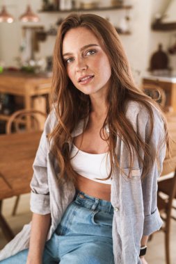 İyimser, mutlu, mutlu, evde oturan kızıl saçlı kadın..