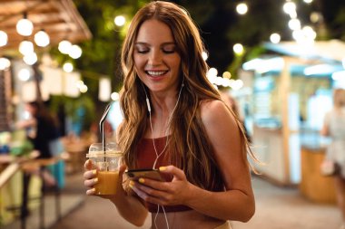 İyimser mutlu kadın cep telefonu kullanarak sokakta yürüyor..