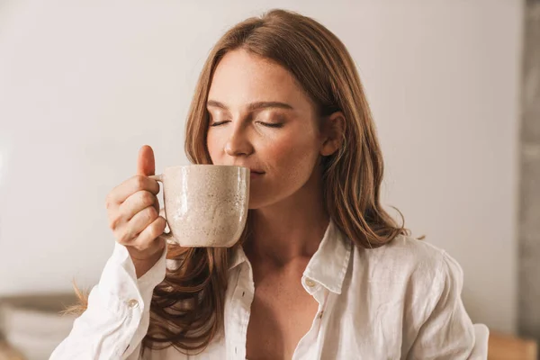 Ginger business woman sit indoors in office drinking coffee. — Stock Photo, Image