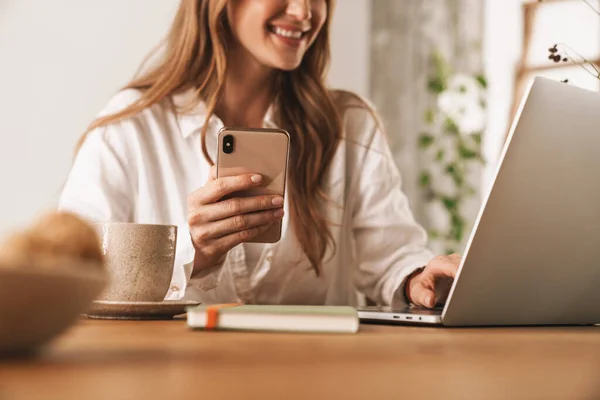 Glimlachende gember zakenvrouw met behulp van laptop computer en mobiele telefoon. — Stockfoto