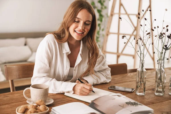 Happy optimistic business woman sit indoors in office writing notes. — Stock Photo, Image