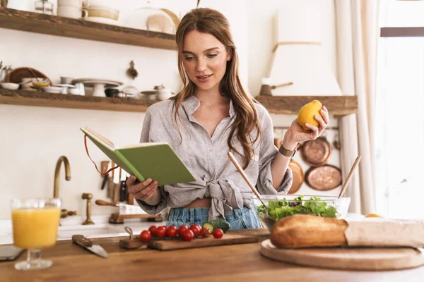 Mulher dentro de casa na cozinha, segurando notebook e limão . — Fotografia de Stock