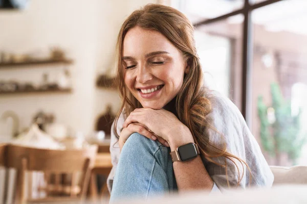 Lächelnd glücklich rothaarige Frau drinnen sitzt in der Küche zu Hause. — Stockfoto