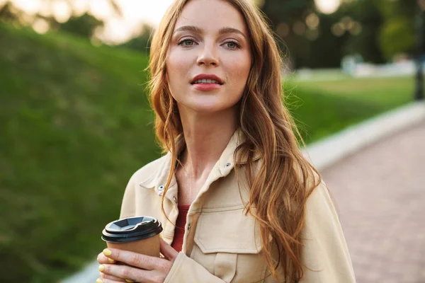 Gember vrouw wandelen in natuurpark het drinken van koffie. — Stockfoto