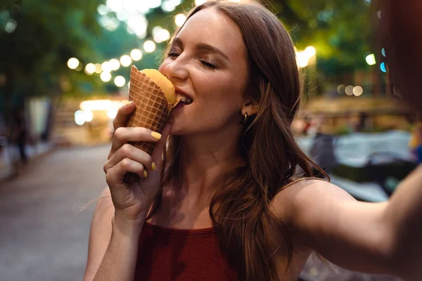 Vacker ung ingefära kvinna ta selfie med kamera äta glass. — Stockfoto