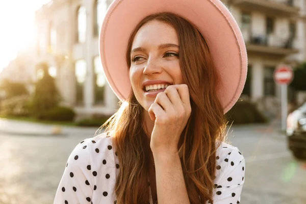 Redhead woman walking by street outdoors in dress and hat. — Stock Photo, Image