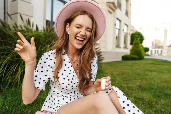 Emotional cheery redhead woman listening music with earphones. — Stock Photo, Image