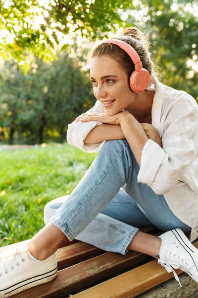 Lovely young girl casually dressed sitting on a bench — Stock Photo, Image