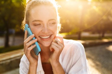 Şehir parkında yürüyen gülümseyen genç bir kızın yakın çekimi.