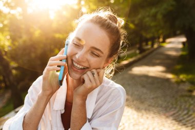 Şehir parkında yürüyen gülümseyen genç bir kızın yakın çekimi.