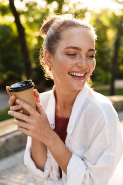 Şehir parkında yürüyen gülümseyen genç bir kızın yakın çekimi.