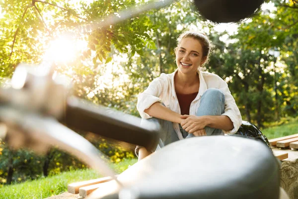 Güzel bir genç kız, sıradan giyinmiş, bankta oturuyor.