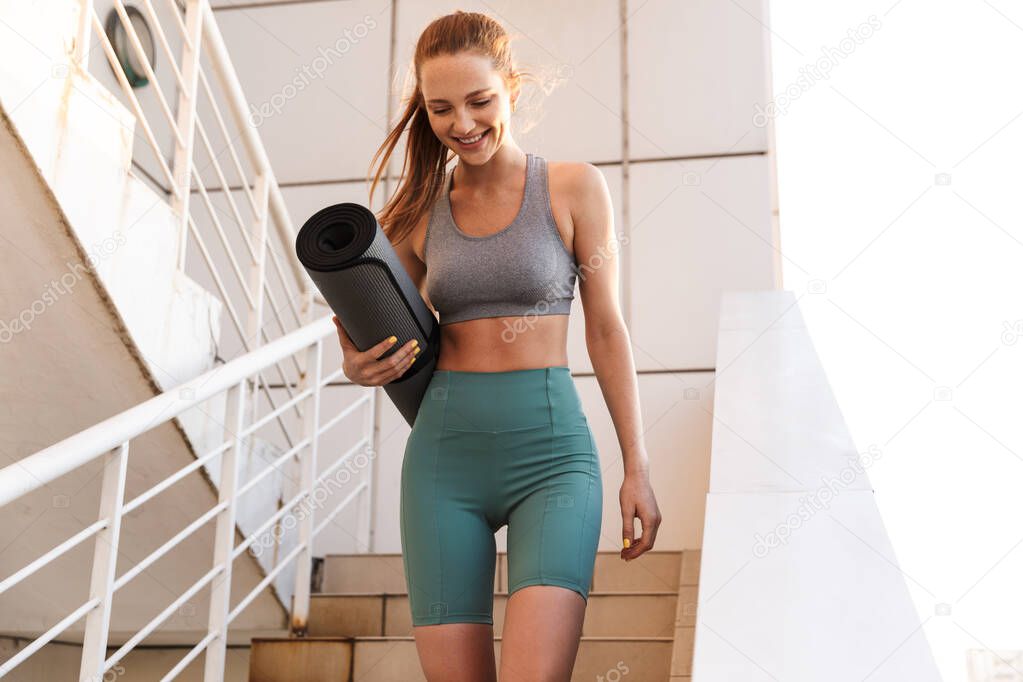 Smiling fit young sportsgirl walking down a staircase